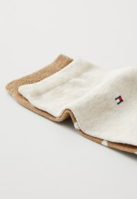 Kniehoge sokken in beige en goud met een zachte textuur. Eén paar heeft een gouden accent, terwijl het andere een subtiel crèmekleurig patroon heeft.