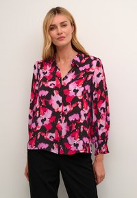 Bloes met bloemenpatroon in zwart, roze en rode tinten. Lange mouwen met elastische manchetten, knopenfront en kraag. Lichtgewicht stof.