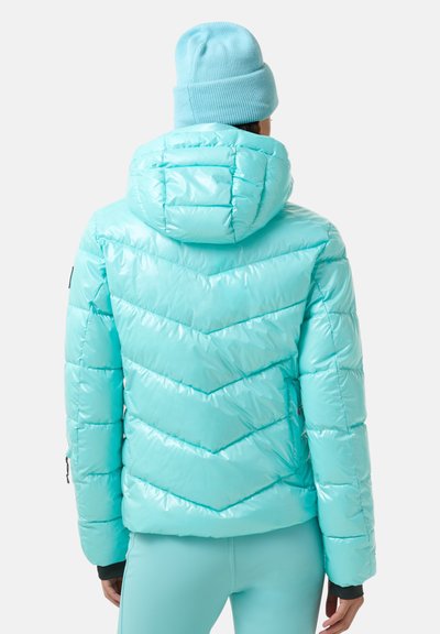 Mintgroene gewatteerde jas met capuchon, voorzien van een chevronsteek en een glanzende afwerking. Gecombineerd met een bijpassende gebreide muts.