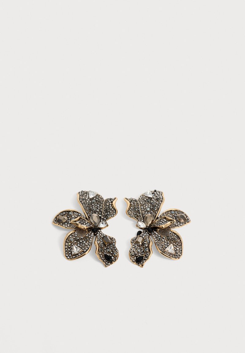 Paire de boucles d'oreilles en forme de fleur de couleur or avec des strass noirs et clairs sur fond blanc.