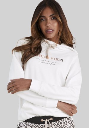 White hoodie with front print reading "Future Vibes" in gold and dark text. Features a drawstring hood and ribbed cuffs, worn with leopard print bottoms.