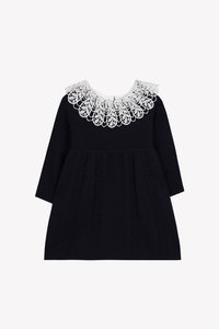 Tmavomodré pletené detské šaty s dlhými rukávmi, vybavené zložitým bielym čipkovým golierom a copánkovým vzorom na sukni a rukávoch.