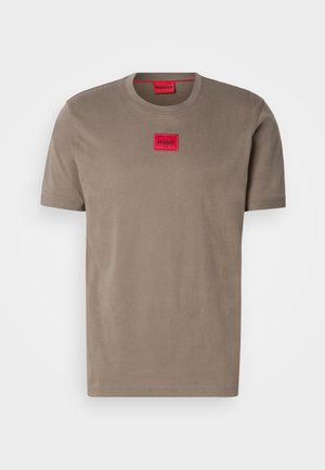 Khaki t-shirt made of cotton, featuring a round neckline and short sleeves. Notable red logo patch at the chest. Smooth texture.