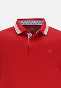 Röd polo t-shirt med krage som har blå och vita ränder, treknapps placket och mönstrad innerfoder. Varumärkeslogotyp på bröstet.