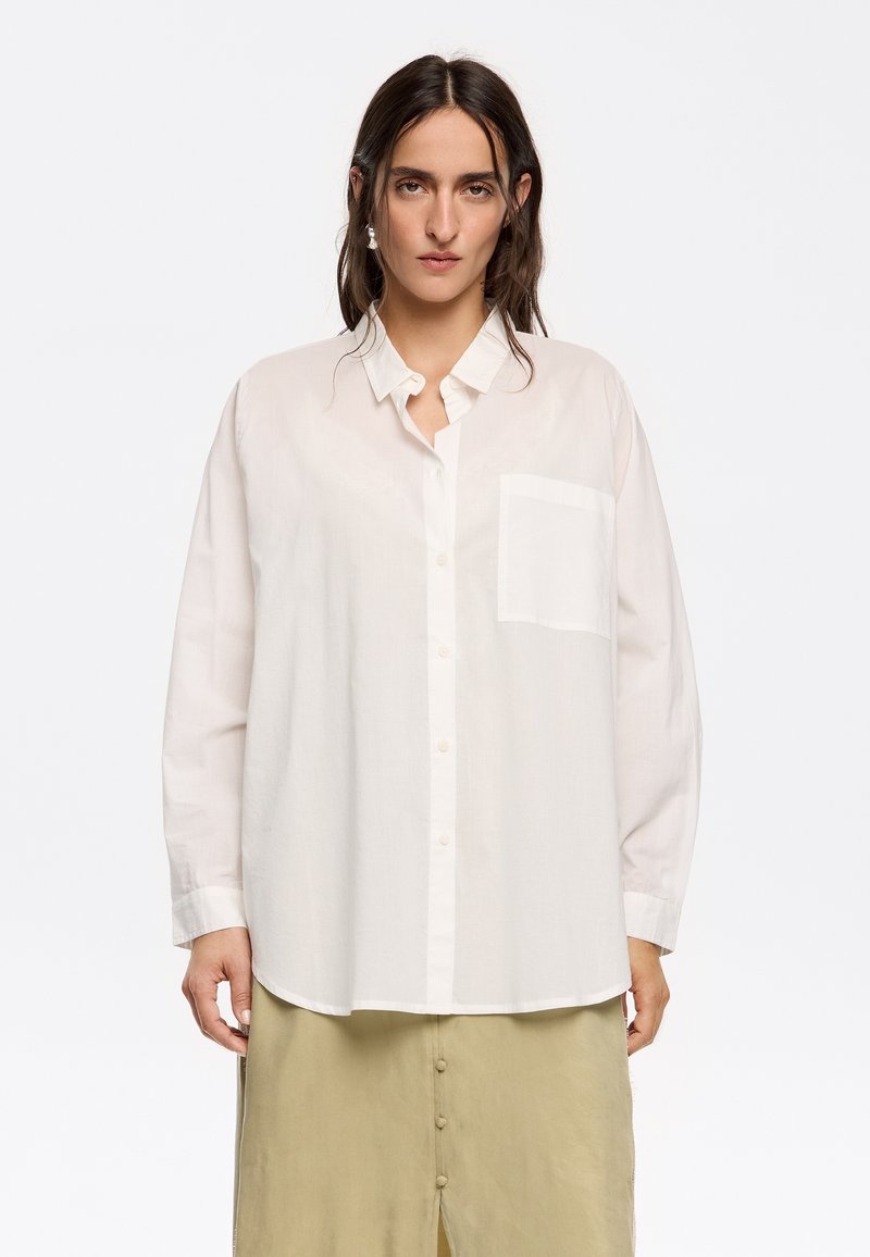 Witte lange mouwen button-up shirt gemaakt van lichtgewicht stof, met een patchzak aan de linkerkant en een ontspannen pasvorm.