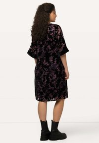 Musta samettimekko, jossa on violetteja ja vaaleanpunaisia kukkakuoseja, polvipituinen, löysä malli, leveät hihat, yhdistetty mustiin nilkkabootseihin.