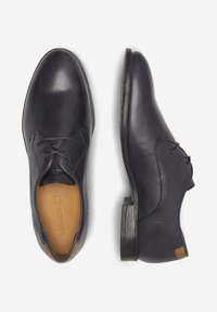 Ciemnoniebieskie skórzane buty o gładkim wykończeniu. Posiadają sznurówki, jasnobrązową wkładkę i obcas o drewnianej fakturze. Solidny, czysty design.