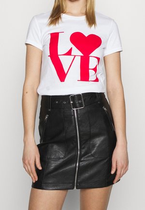 Kobieta w białym t-shircie z czerwonym napisem ""LOVE"" i sercem, połączonym z wysokim czarnym skórzanym spódnicą z zamkiem z przodu i paskiem.