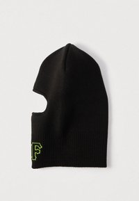 Balaclava neagră tricotată cu o deschidere pentru un singur ochi și litere brodate neon verde lângă marginea de jos.