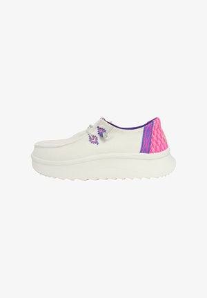 Zapatilla de lona blanca con una suela gruesa blanca, que presenta un acento texturizado en rosa y morado en el talón y costuras decorativas en el costado.