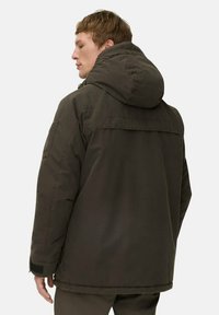 Dunkelgrüne, gepolsterte Jacke mit großer Kapuze, die eine Klapptasche am linken Arm und eine glatte, matte Textur aufweist.