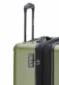 Valigia rigida verde oliva con manico estensibile nero, chiusura a zip e lucchetto approvato TSA sul lato.