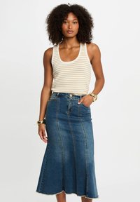 Striped tank top in cream and gold, paired with a high-waisted denim skirt featuring a flared silhouette and raw hem.