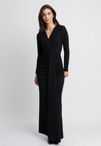 Czarna sukienka z długim rękawem i dekoltem w serek, z marszczoną talią i eleganckim, sięgającym podłogi krojem, wykonana z teksturowanej, błyszczącej tkaniny.