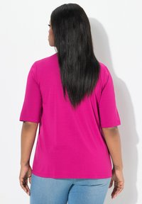Camiseta de manga corta fucsia hecha de material suave, con un corte relajado, que combina con jeans azul claro. Diseño sencillo de color sólido.