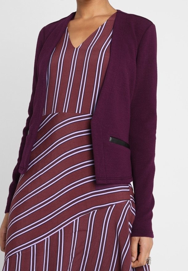 Lila öppen cardigan med texturerad tyg, utan knappar. Matchad med en vinröd klänning med vertikala lila ränder. Svart fickdetalj.