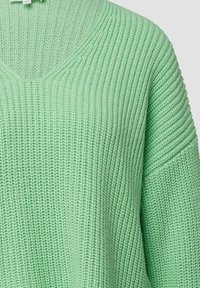 Hellgrüner Strickpullover mit V-Ausschnitt, gerippter Struktur und lockerem Schnitt mit überschnittenen Schultern und weiten Ärmeln.