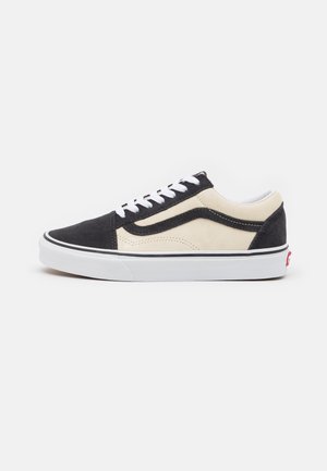 Schwarze und beige Wildleder-Sneaker mit weißen Schnürsenkeln, runder Zehenpartie und Gummisohle; mit einem kontrastierenden Seitenstreifen und einem Logo-Tag.