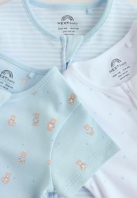 Trois bodies pliés NEXT pour bébé en blanc, rayé bleu clair et bleu clair avec imprimé ourson, montrant des encolures rondes et des étiquettes.