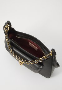 Black leather handbag with a textured finish, gold-tone chain strap, and a burgundy interior. Features a zip closure and interior pocket.