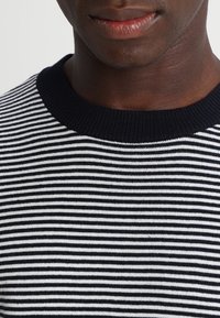 Maglione a righe blu navy e bianche con colletto rotondo a coste, che presenta una texture liscia e linee orizzontali uniformemente distanziate.