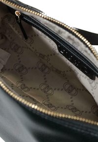 Bolso negro con una textura suave y cremallera dorada. El interior cuenta con una tela con estampado en beige y marrón oscuro.