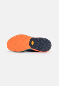 Schoenenzool met een levendige oranje basis, een gestructureerd zwart rubber voor grip en een gele merklogo dat in het midden is ingebed. Algehele gestroomlijnde vorm.