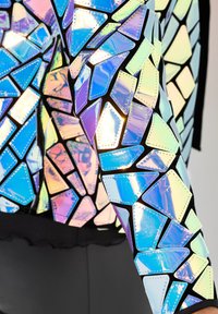 Reflekterende jakke med geometriske, iriserende mønstre i blå og lilla nuancer. Har kontrasterende sorte detaljer og syninger.