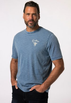 Camiseta de algodón azul con mangas cortas, cuello redondo y una textura suave. Presenta un logo 'Outlaw' de color claro y un gráfico de un toro en el lado izquierdo del pecho.