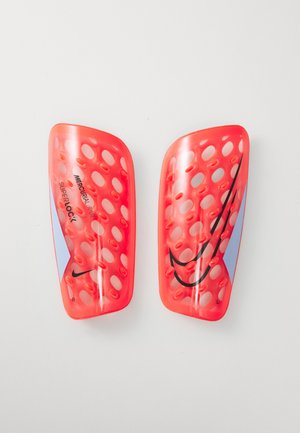 Une paire de protège-tibias de soccer Nike Mercurial Flylite Superlock rouge, avec des trous de ventilation, des logos swoosh noirs et des accents bleus sur un fond blanc.
