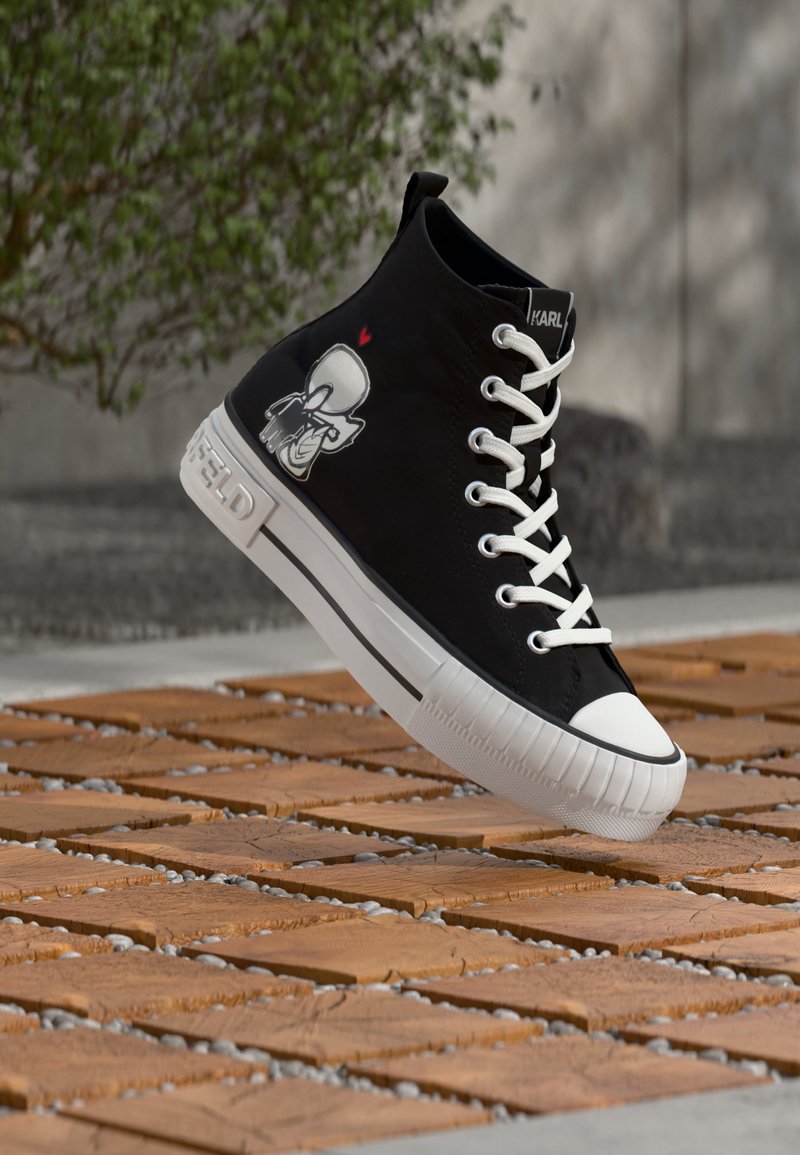 Juodos spalvos aukštos viršaus sportbačiai su baltais raišteliais ir padu, šone pavaizduotas animacinis personažas, plūduriuojantis virš lauke esančios medienos rašto grindų.