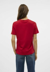 Rode katoenen t-shirt met korte mouwen en een rechte snit, met een eenvoudige ronde hals. Draag het met blauwe denimbroeken.