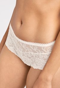 Culottes en dentelle ivoire avec broderies florales, construction en maille et bords festonnés pour une finition délicate.