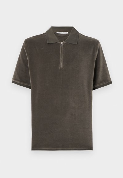 Πόλο πουκάμισο σε βαθύ ελιάς πράσινο χρώμα, από απαλό, υφασμένο ύφασμα, με φερμουάρ στο ένα τέταρτο και κοντά μανίκια με ριμπ τελείωμα.