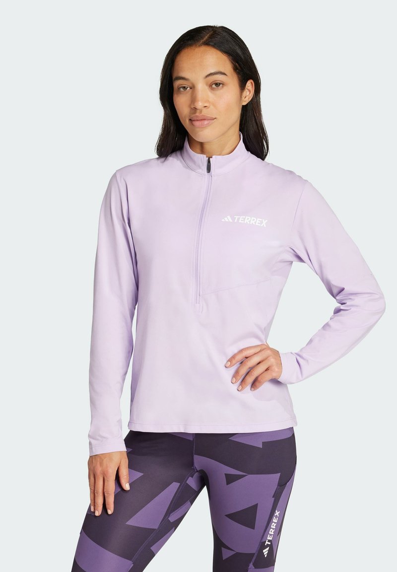 Light purple zip-up long-sleeve top with a raised collar, featuring a small logo on the chest and a textured fabric.