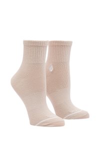 Calcetines tobilleros beige hechos de una tela suave, con un puño acanalado y un logo blanco. Textura lisa con un ajuste ceñido.