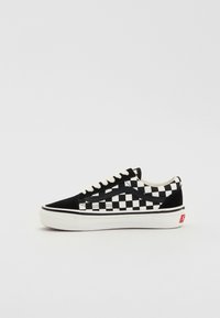 Zapatillas de lona en blanco y negro con diseño de tablero de ajedrez, con parte superior de ante, suela de goma blanca y detalles en negro en los laterales y los cordones.