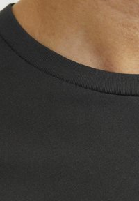 T-shirt in cotone nero con collo a girocollo a coste e texture liscia, che mostra un primo piano del tessuto e della zona del collo.