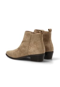 Botas de tobillo de ante beige con punta afilada, cremallera lateral y tachuelas metálicas a lo largo de la costura exterior; tacón bajo apilado.
