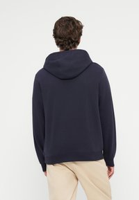 Námornícky modrá mikina s kapucňou, hladkým povrchom, rebrovanými manžetami a voľným strihom, s klokanou kapsou a čistými švami.