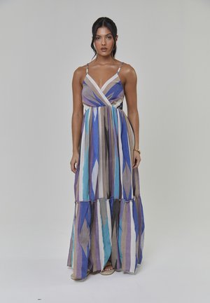 Robe longue avec un motif géométrique multicolore en bleu, violet et beige. Confectionnée en tissu léger avec une coupe à volants et des bretelles fines.