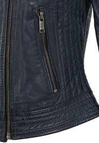 Veste en cuir bleu marine avec une poche zippée, texture matelassée et couture contrastante le long des bords et des coutures.