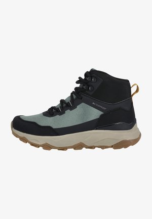 Bottes de randonnée imperméables avec une tige en tissu vert menthe, des surpiqûres synthétiques noires, une semelle beige épaisse et une boucle de traction à l'arrière.