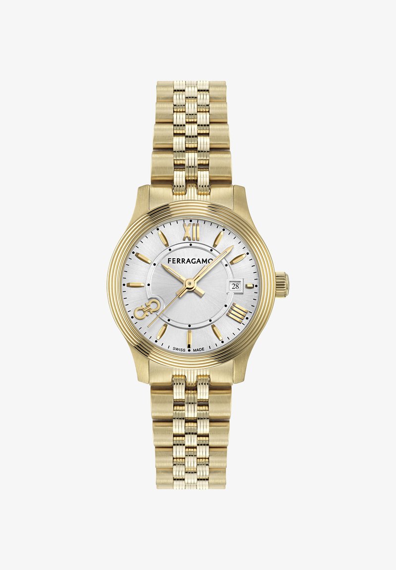 Zelta krāsas pulkstenis ar sudraba ciparnīcu, kurā ir romiešu skaitļi, datuma logs un saistīta metāla aproce. Šveicē ražots.