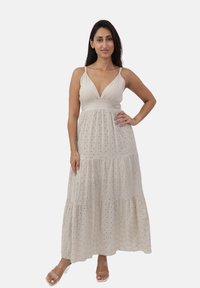 Maxi abito beige chiaro con scollatura a V profonda e spalline regolabili. Presenta un design a strati con tessuto testurizzato e delicati dettagli ad occhio di pernice.