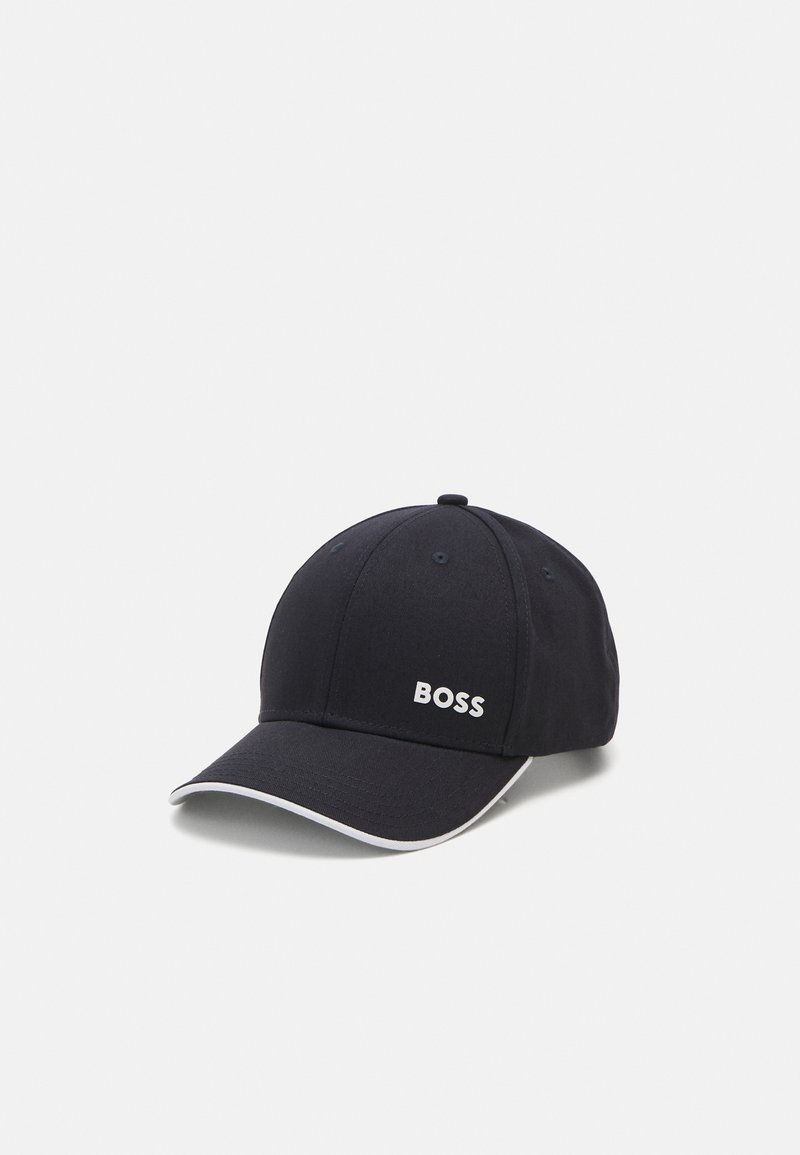 Jūras zila cepure, kas izgatavota no auduma ar izliekto mali, kurai ir balta "BOSS" logo un kontrastējoša balta dūriena apmales malā.