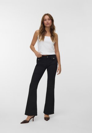 Black flared trousers made of cotton blend fabric, featuring front pockets and button accents. Paired with a white sleeveless top.