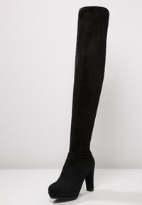 Czarne, zamszowe kozaki za kolano, z wysokim blokowym obcasem i platformą, o gładkiej fakturze i dopasowanym kroju.
