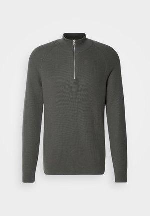 Pull en maille côtelée gris foncé avec un col haut et une courte fermeture éclair au niveau du cou. Comprend des manches longues et une silhouette ajustée.