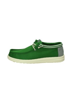 Scarpa slip-on verde in tela con accento grigio chiaro sul tallone, caratterizzata da una suola in gomma bianca e due dettagli decorativi a forma di lacci.